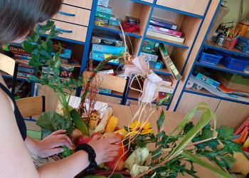 Powiększ zdjęcie: Uczennica przygotowuje kosz z warzywami i owocami.