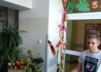 Powiększ zdjęcie: Uczeń z kukurydzą obok koszy z warzywami i owocami.