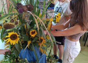 Powiększ zdjęcie: Uczniowie przygotowują kompozycję z kwiatów, kukurydzy i zbóż.