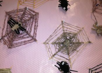 Powiększ zdjęcie: Pajęczyny z pająkami wykonane z włóczki, patyczków i papieru kolorowego.