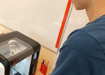 Powiększ zdjęcie: Uczeń wyjmuje z drukarki 3D wydrukowane żonkile.
