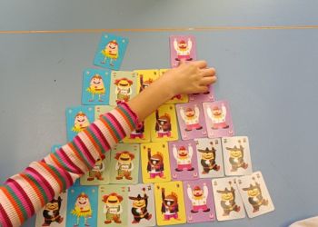 Powiększ zdjęcie: Uczniowie grają w gry karciane - układają z kart piramidę.