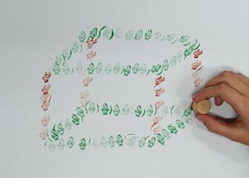 Powiększ zdjęcie: Tworzenie przez ucznia modelu prostopadłościanu z mikołajkowych pieczątek.