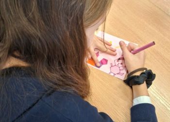 Powiększ zdjęcie: Uczennica wykonująca mozaikę z czworokątów i innych wielokątów.