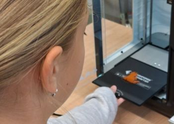 Powiększ zdjęcie: Uczennica wyjmuje breloczek w kształcie kotka 3D z drukarki 3D.