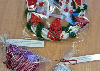 Powiększ zdjęcie: Ozdoba na kiermasz - wianek z łańcucha na choinkę, gwiazdek z brokatu, wstążki, drewnianych prezentów i Mikołaja z filcu, bombka z kolorowego papieru, cekinów, gwiazdek i łańcucha na choinkę oraz sznurków, but z drewna i kolorowego łańcucha z pomponami - z bilecikami z napisem Zespół Szkół Specjalnych w Skoczowie – Oddziały w Beskidzkim Zespole Leczniczo-Rehabilitacyjnym w Jaworzu.