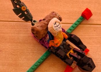 Powiększ zdjęcie: Ułożony pojazd z klocków LEGO z postacią w nim siedzącą z plasteliny.