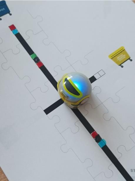Robot Ozobot poruszający się po trasie w kierunku pojemnika na tworzywa sztuczne plastik i metale.