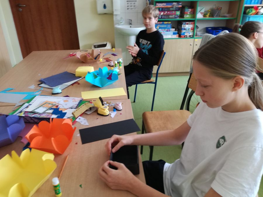 Uczniowie składający pudełko na prezenty metodą origami.