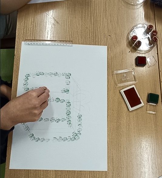 Tworzenie przez ucznia modelu prezentu z mikołajkowych pieczątek.