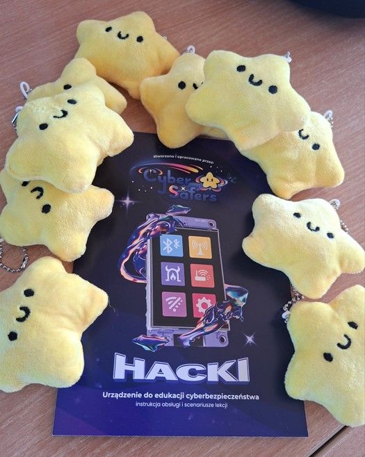 Breloczki w kształcie gwiazdki otrzymane od zespołu projektu CyberSafers wraz z broszurą stworzoną i opracowaną przez CyberSafers – Hacki, Urządzenie do edukacji cyberbezpieczenstwa instrukcja obsługi i scenariusz lekcji.